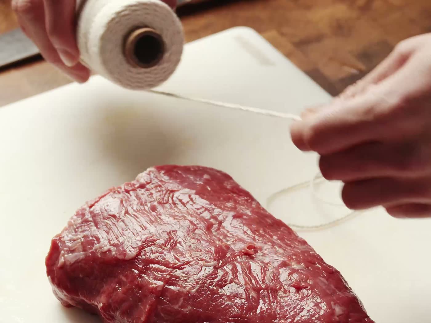 Mains du boucher ficelant un rôti au fil de lin