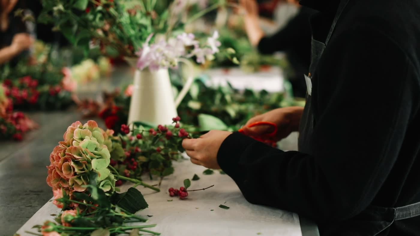 Mains de la fleuriste composant à l'atelier