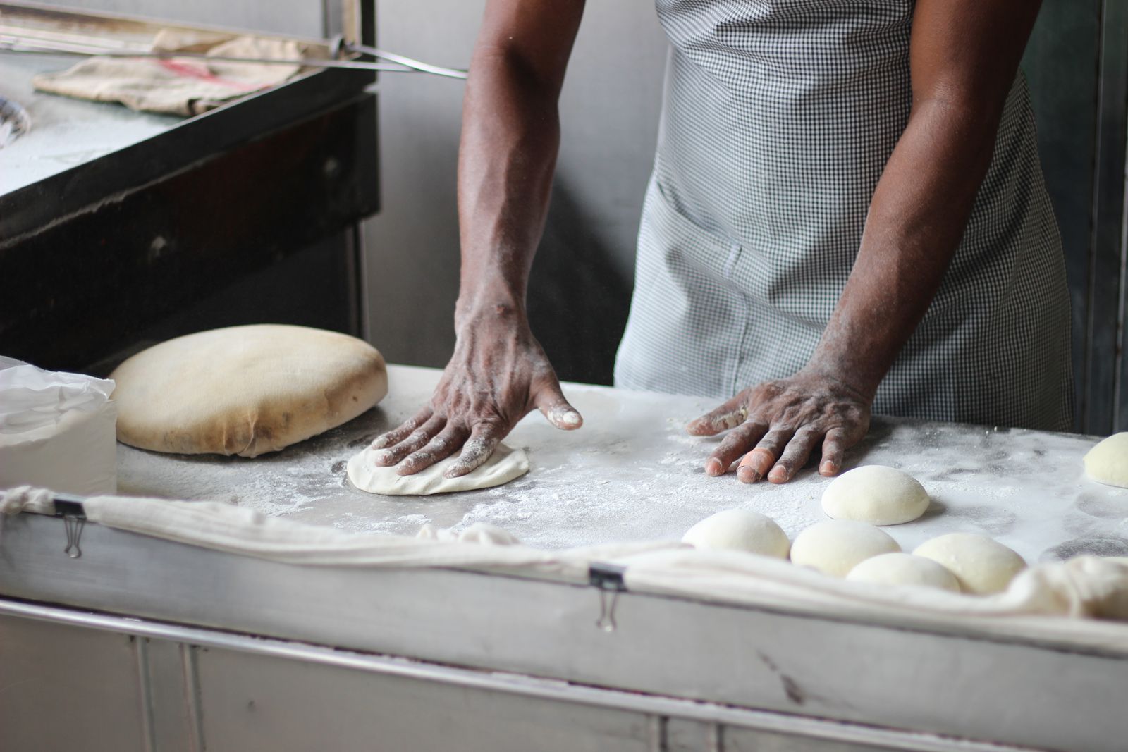 Les mains du boulanger façonnant les pâtons sur la table farinée