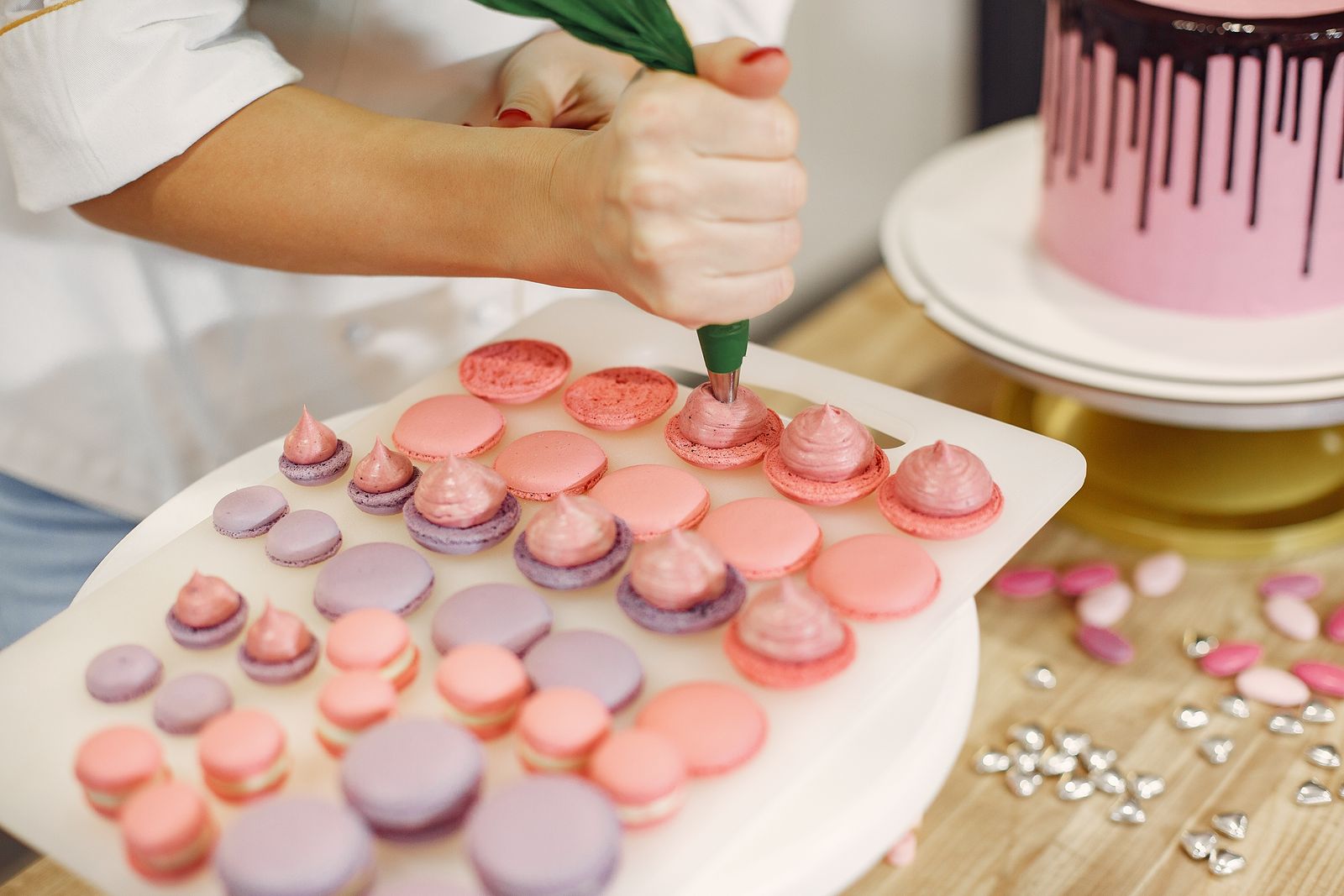 Le pâtissier garnit les coques de macarons à la poche
