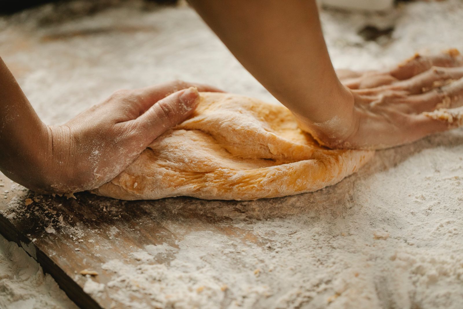 Mains du pâtissier étirant la pâte sur le plan fariné