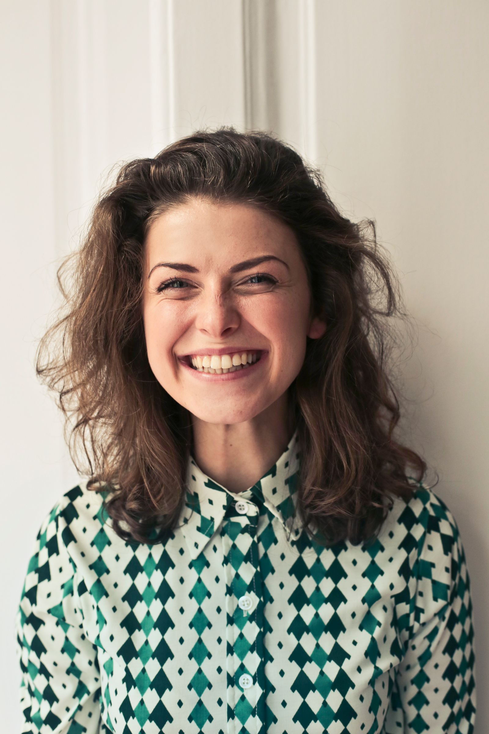 Portrait de femme souriante à la lumière de la fenêtre, fond clair