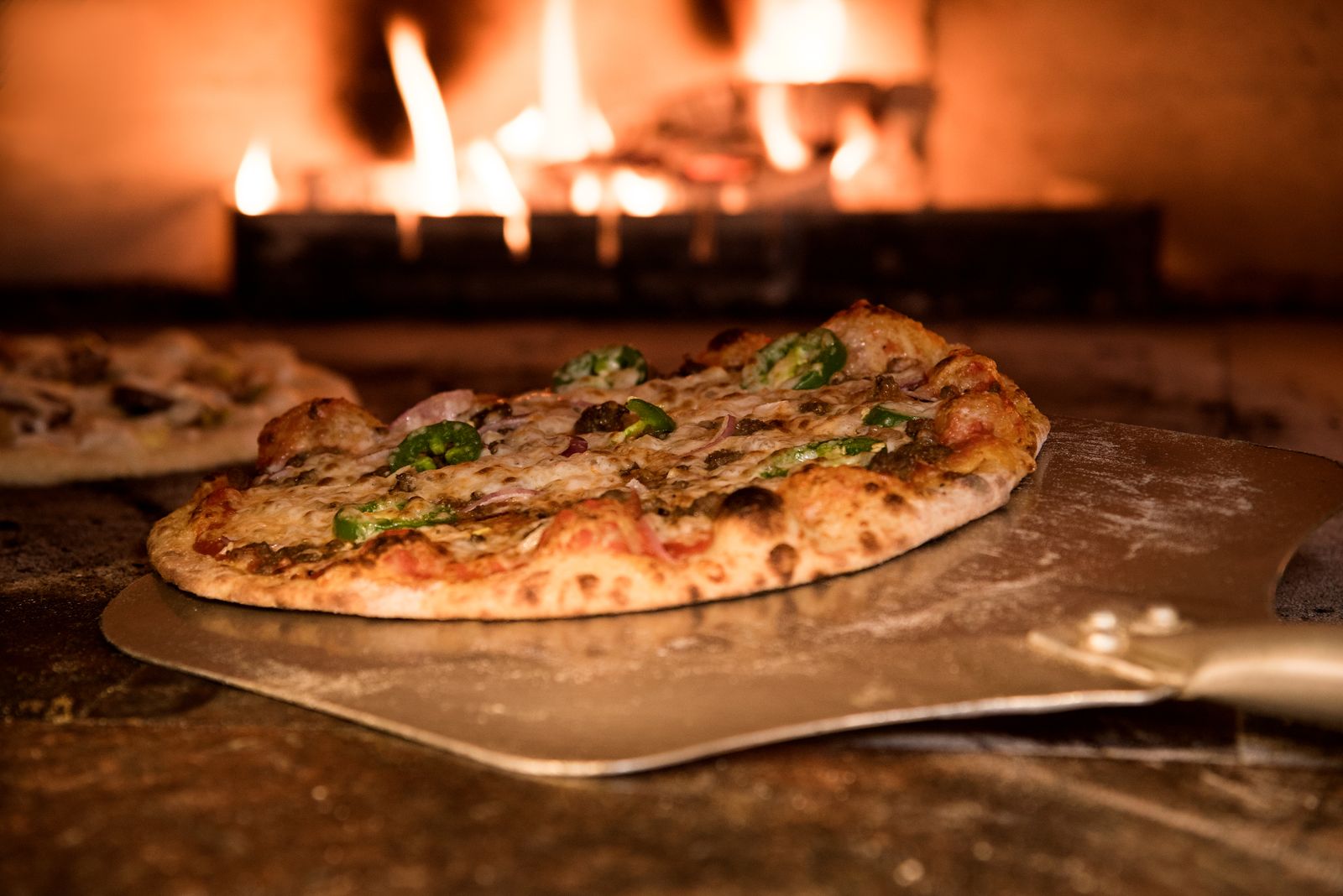 Pizza sortant du four à bois sur sa pelle