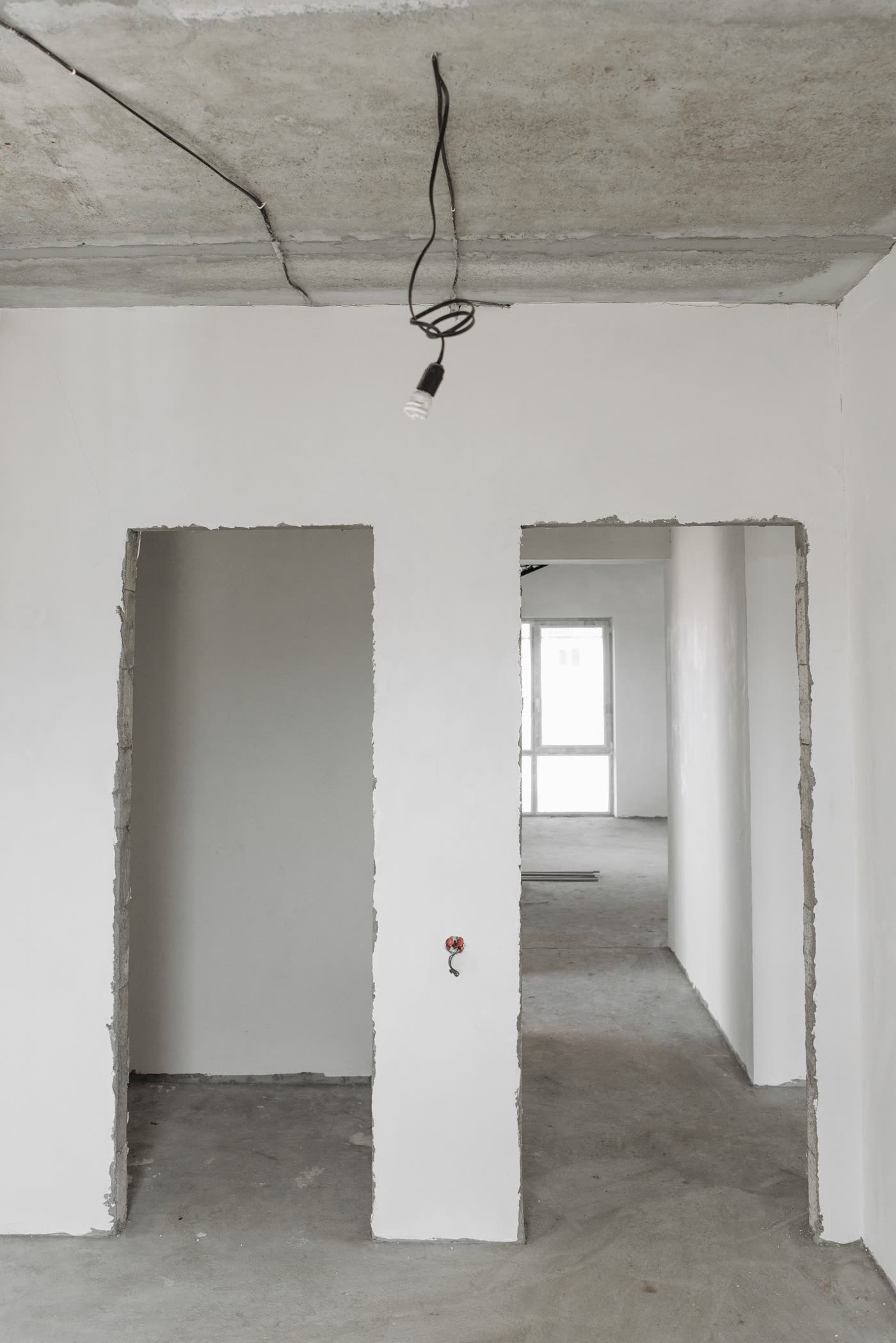 Pièce aux murs d'enduit gris, cloison ouverte pendant les travaux