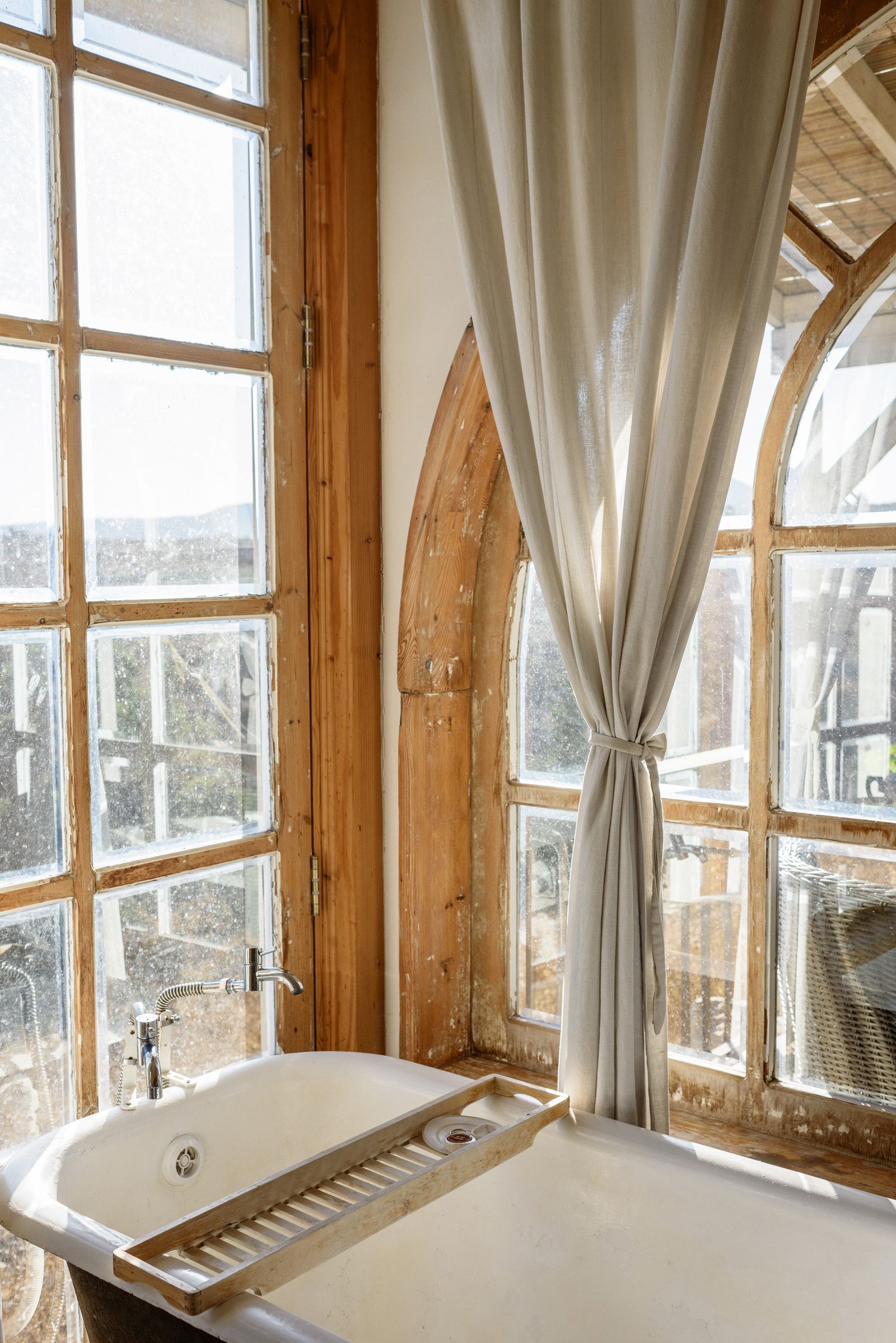 Une baignoire ancienne sous les grandes fenêtres d'une salle de bain du domaine